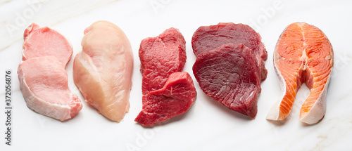 Keto high fat products. Meat and fish on white marble background.