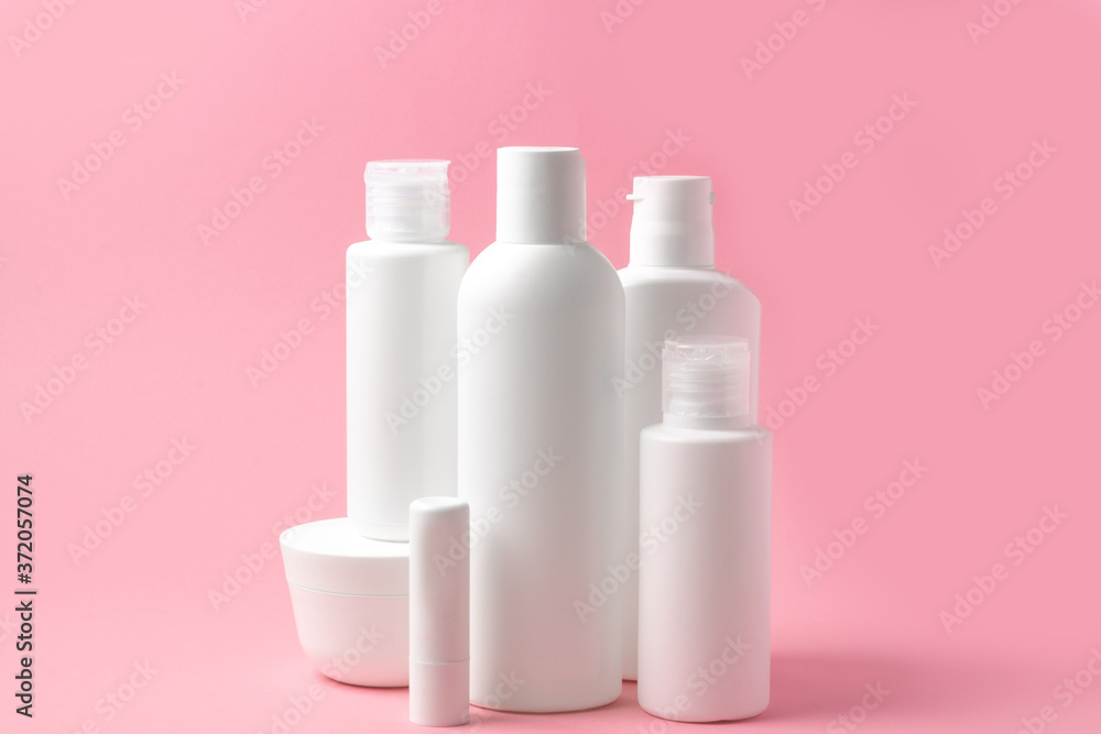 Set of white cosmetic bottles and jars on pink background with place to add text Set of white cosmetic bottles and jars on pink background with place to add text