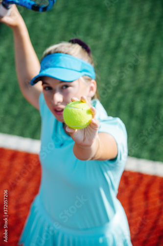Focused girl training on a new tennis court, throwing ball up and serving © zzzdim