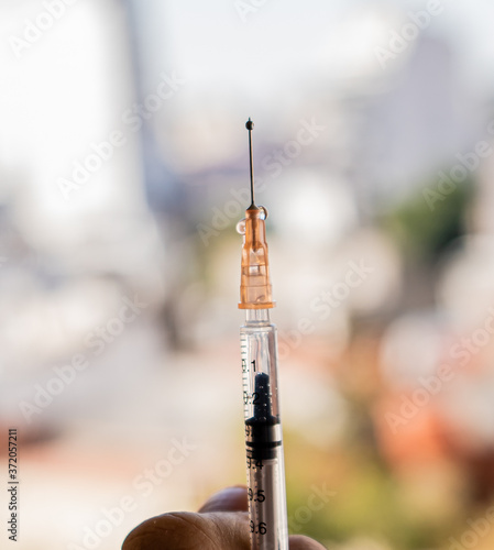 Jeringa, vacuna con la ciudad de fondo 