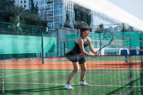Focused teenage girl playing tennis, holding stance, balancing between feet