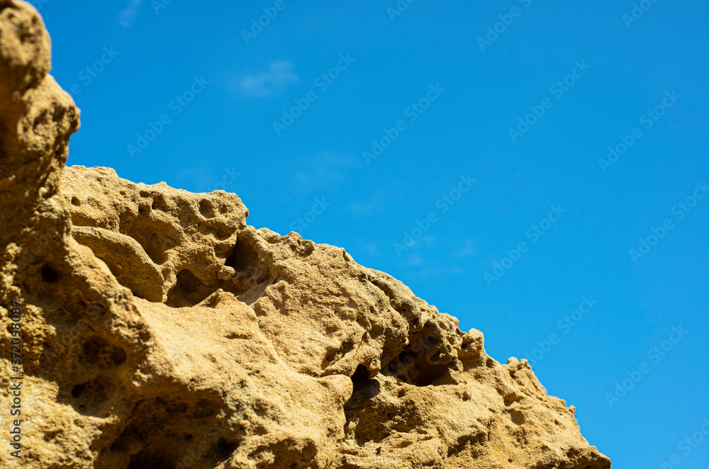  Rock texture on a background of blue sky. The porous perforated texture of the stone. Coastal rocks.