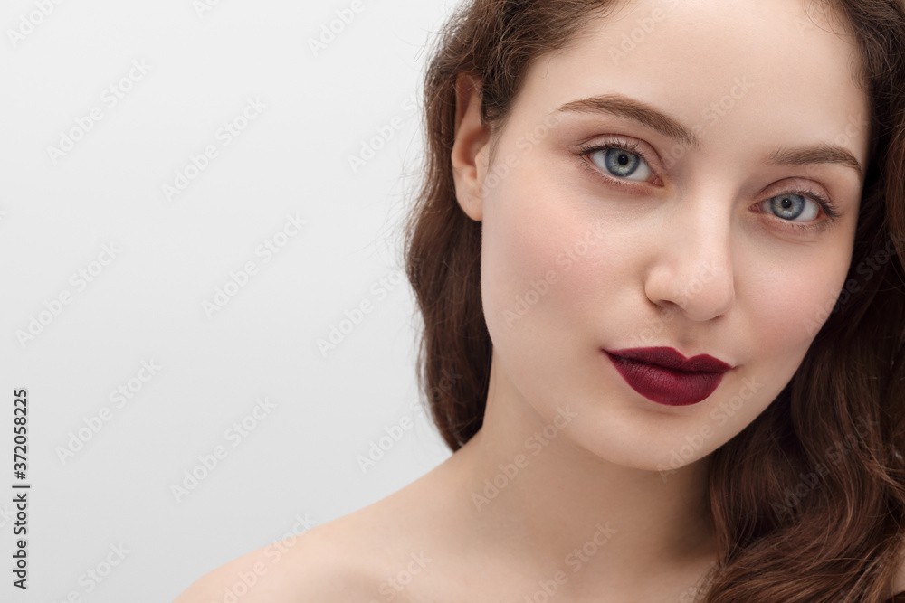 Young girl with burgundy lipstick on her lips, long hair, close-up. Young girl with long hair and blue eyes. Young girl with burgundy lipstick on her lips, long hair, close-up. Young girl with long hair and blue eyes.