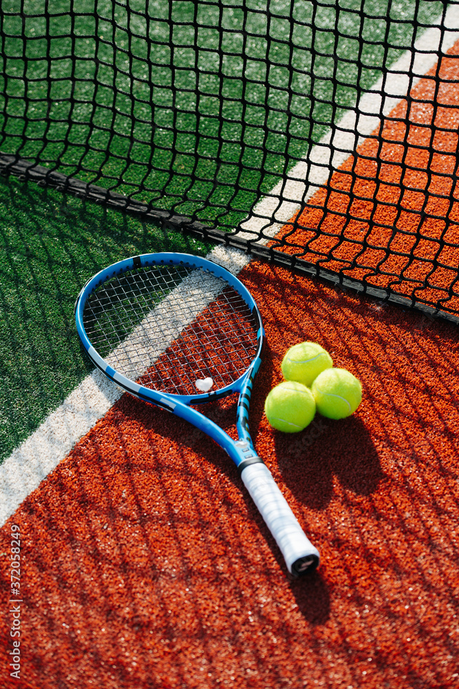 Tennis racket lying on the line between inner ond outer court next to the net