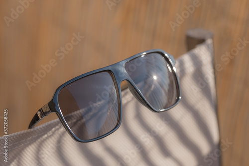 Retro aviator sunglasses model with black lenses and black frame plastic material reflecting the sun in a summer day closeup . Selective focus