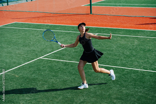 Running teenage girl ready to return overhead tennis ball