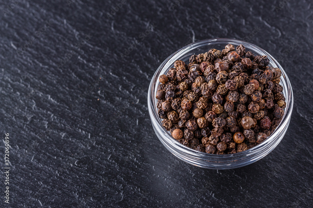 aromatic black pepper on a dark stone background aromatic black pepper on a dark stone background