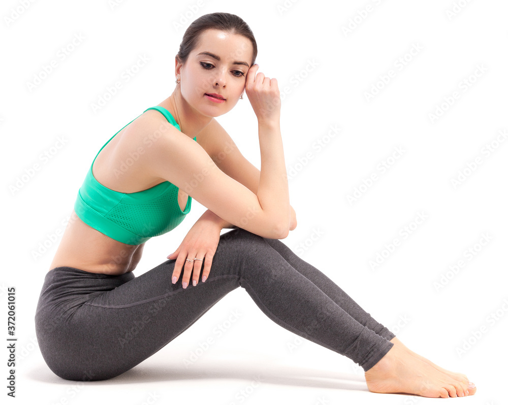 Fitness woman resting while sitting on the floor against white background. Fitness woman resting while sitting on the floor against white background.
