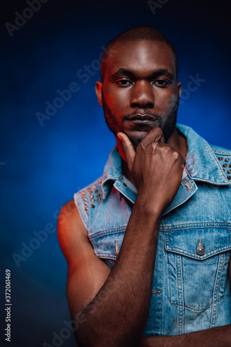Blue smoky background and casual guy. Stylish quality urban clothes and african man dressed in it. Casual jean clothes.