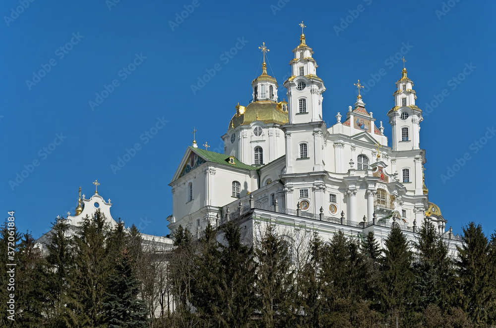 Dormition Cathedral of Holy Dormition Pochayiv Lavra, Ukraine seen over the pinewood.