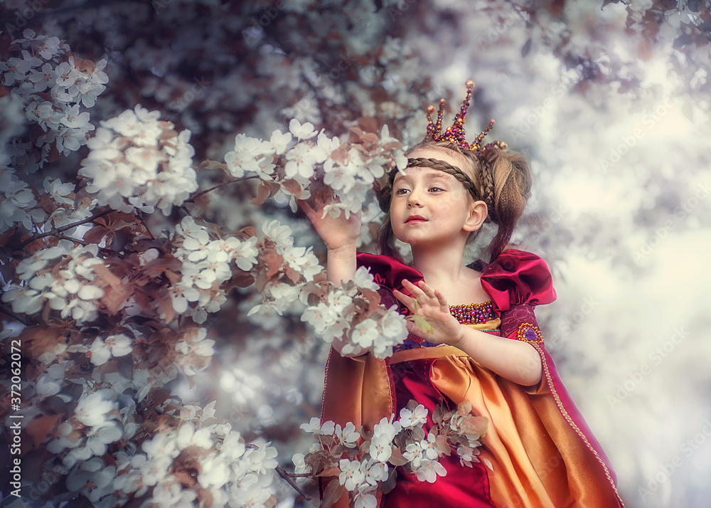 Fototapeta premium A little Princess in Apple blossom touches the flowers.