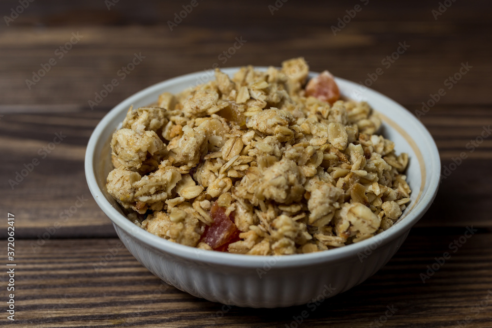 granola in a white bowl with pieces of tropical fruits granola in a white bowl with pieces of tropical fruits