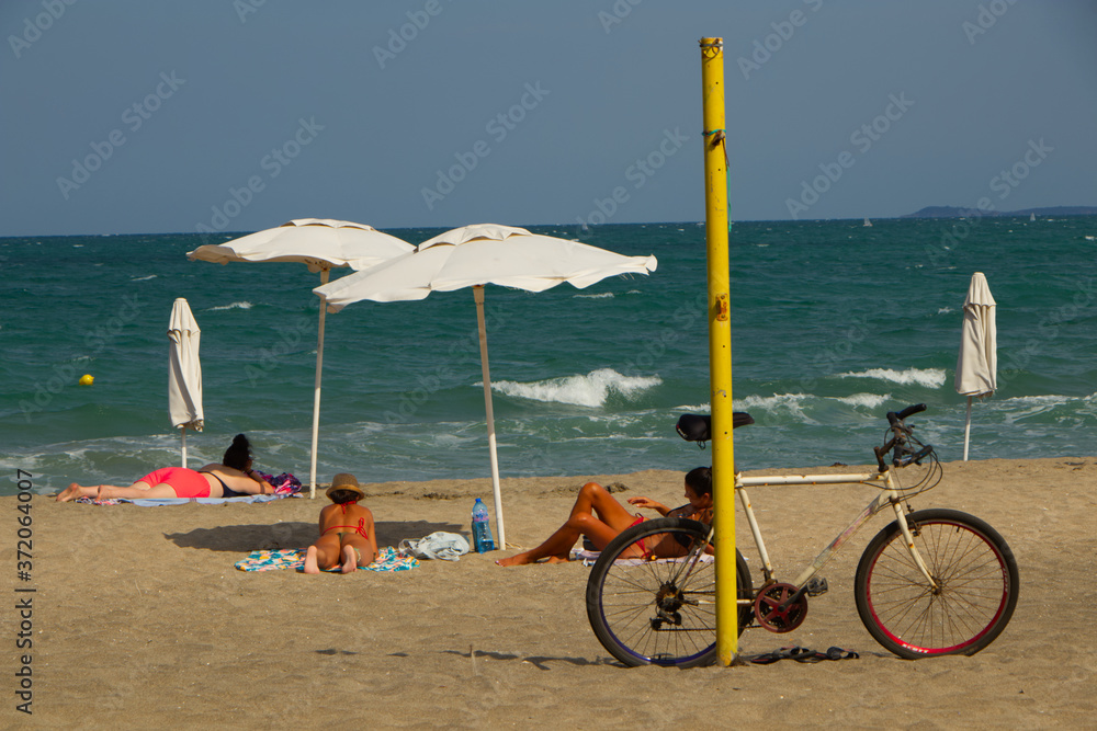 Women sunbathing on the beach and a bicycle Women sunbathing on the beach and a bicycle