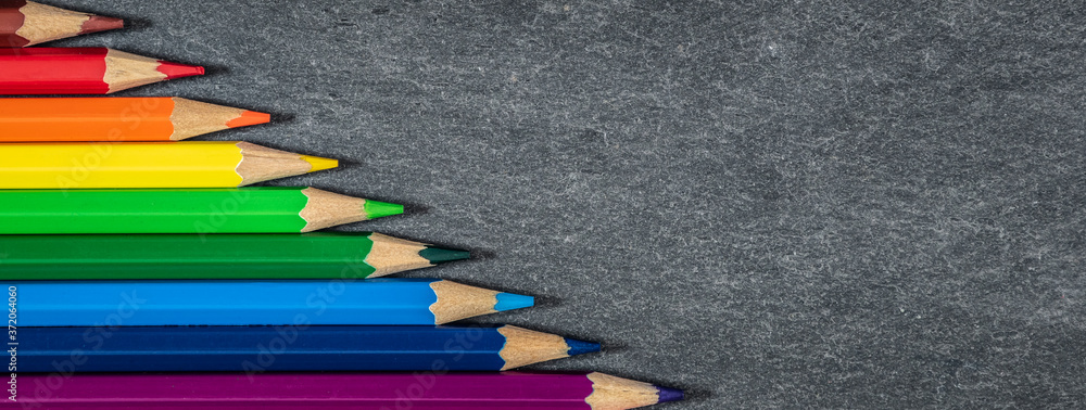 Colored pencils on slate background. Drawing and art banner. 