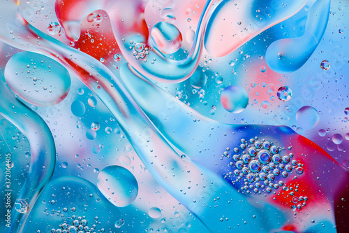 Close-up of the movement of oil droplets on the water surface. Colorful abstract macro background of oil drops on the water surface.