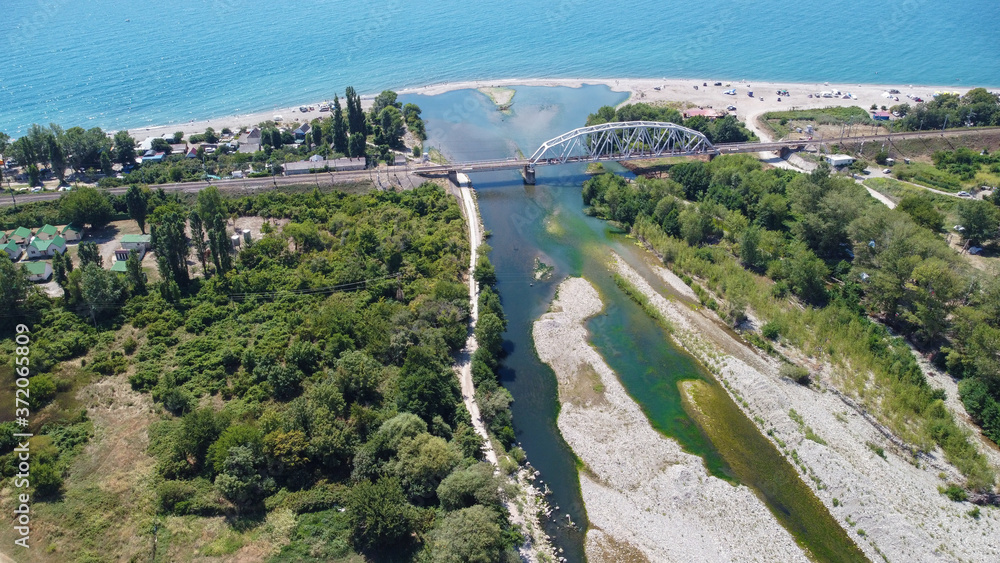 Aerial view of the Shakhe river flowing into the Black sea and the railway bridge over the river. Sochi, Russia. 