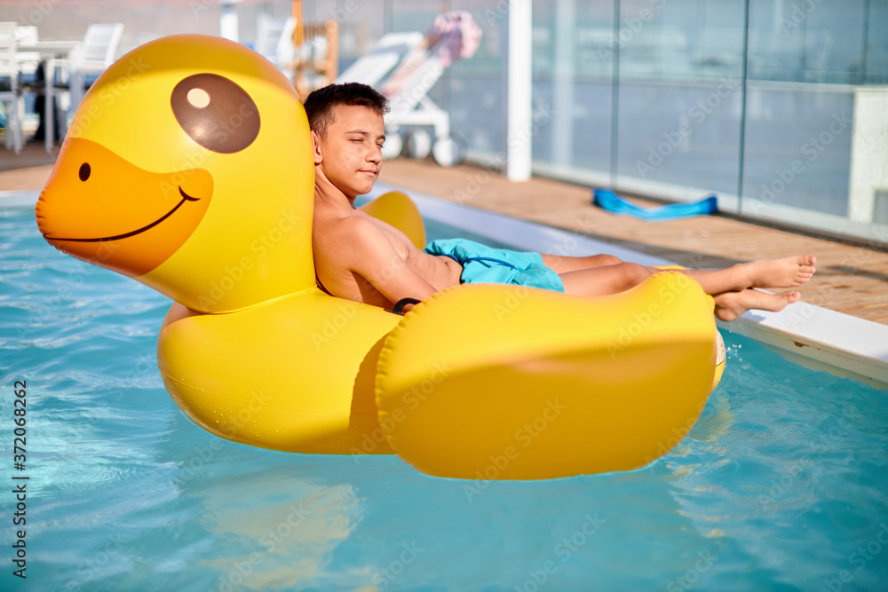 little boy is relaxing on Yellow Duck at pool. Background of travel in summer holiday
