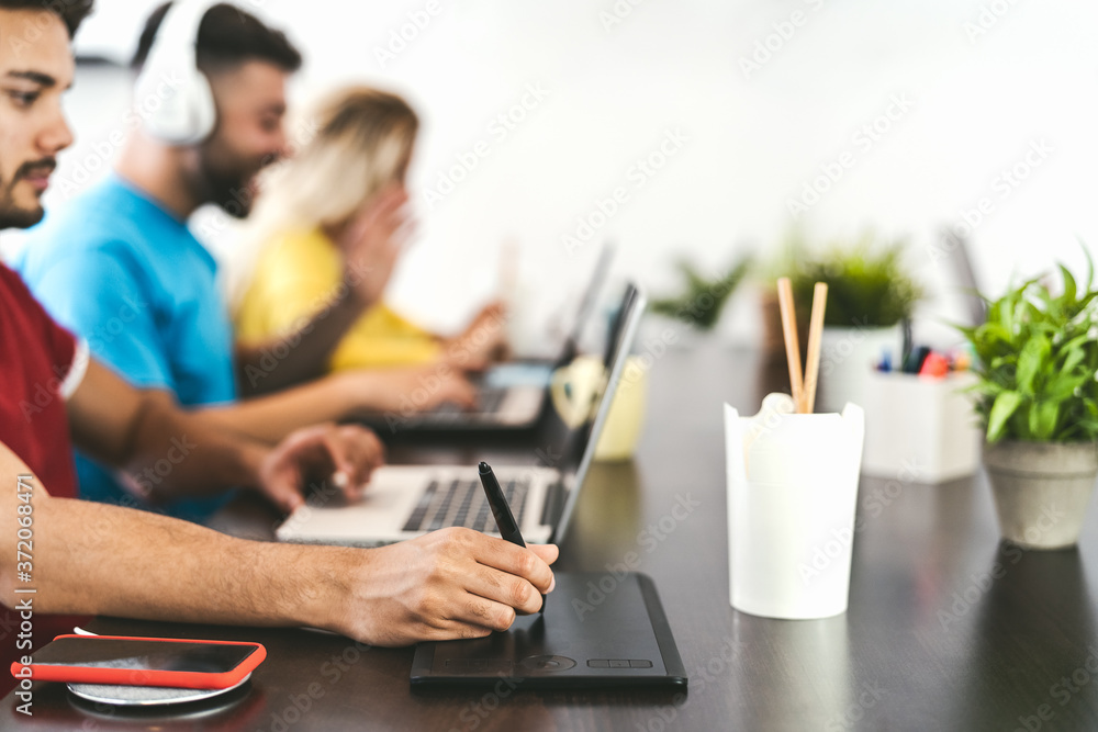 Young friends working together inside co-working creative space - Millennial people doing startup strategy in modern office - Youth generation and technology concept Young friends working together inside co-working creative space - Millennial people doing startup strategy in modern office - Youth generation and technology concept