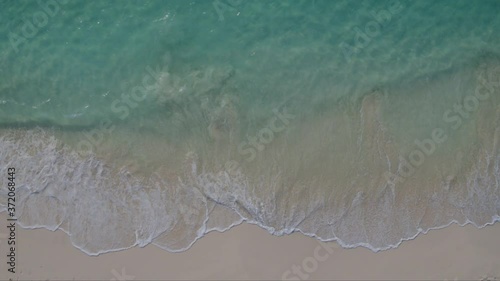 Aerial top down static drone shot of turquoise Caribbean sea gently lapping onto perfect sandy beach.