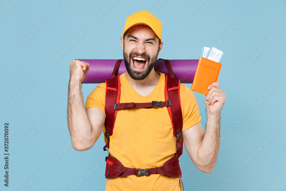Happy traveler young man in t-shirt cap with backpack isolated on blue background. Tourist traveling on weekend getaway. Tourism discovering hiking concept. Hold passport tickets doing winner gesture. Happy traveler young man in t-shirt cap with backpack isolated on blue background. Tourist traveling on weekend getaway. Tourism discovering hiking concept. Hold passport tickets doing winner gesture.