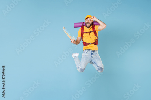 Full length portrait Excited young traveler man in t-shirt with backpack isolated on blue background. Tourist traveling on weekend getaway. Tourism discovering hiking concept. Jumping hold city map.