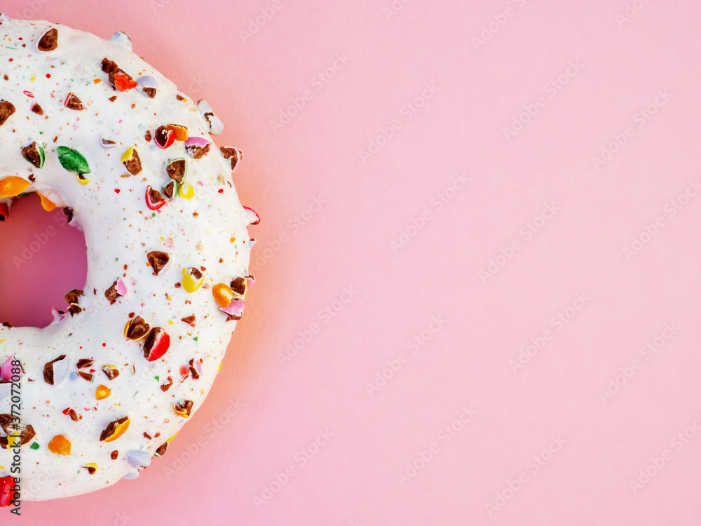 Half circle donut with white icing and choclate rainbow sprinkles on a trendy pink background. Tasty doughnutdonut, top view. Sweet food leftlovers. Unhealthy calorie food Half circle donut with white icing and choclate rainbow sprinkles on a trendy pink background. Tasty doughnutdonut, top view. Sweet food leftlovers. Unhealthy calorie food