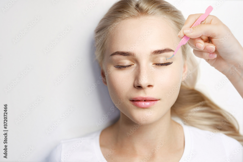 Beautiful young woman  in beauty salon. Woman getting facial treatment. Perfect trendy eyebrows and eyelashes. Eyelash Extension Procedure.