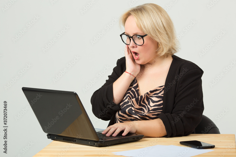beautiful young woman on a white background in glasses at the table with a laptop beautiful young woman on a white background in glasses at the table with a laptop