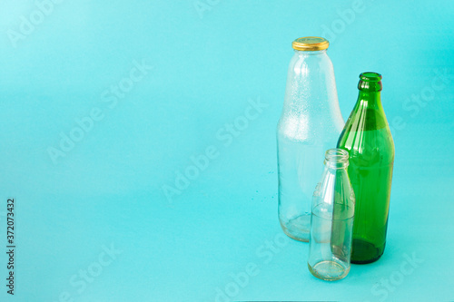 Empty glass transparent and green bottles on a blue background. A copy of the space. Ecology and Zero waste concept