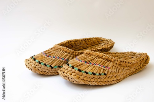 Straw slippers white background. Wicker slippers. Ancient home shoes white background.