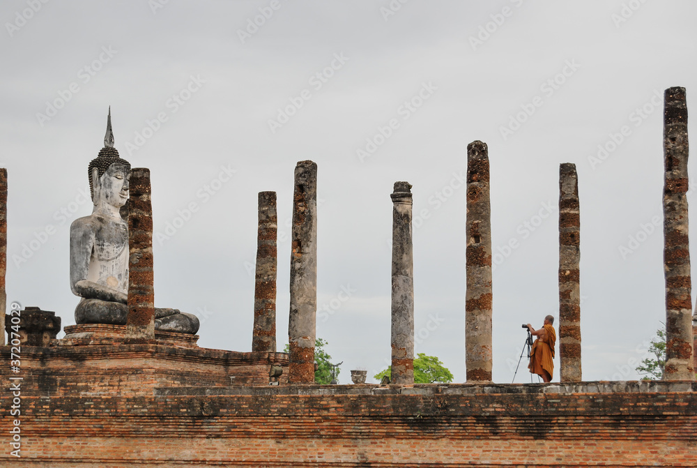 Buddhist monk taking pictures at Wat Mahathat ancient capital of Sukhothai Thailand. 