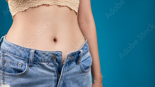 Beautiful sexy body, close-up, belly of a slender women, blue background © vell
