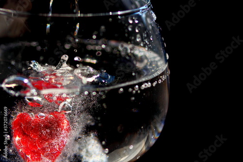 Fresh raspberry dropped in fizzy drink in glass photo