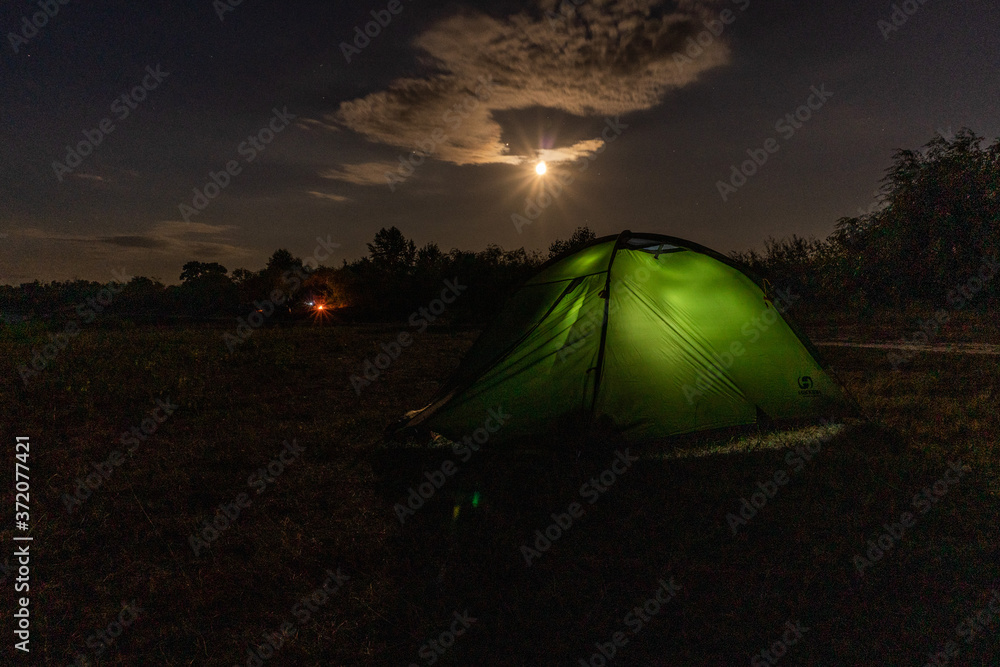 Cloudly night sky with moon and tent