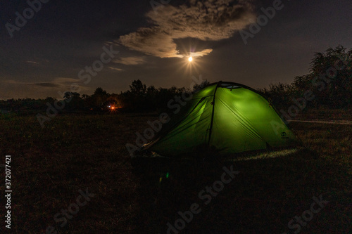 Cloudly night sky with moon and tent