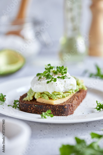 Healthy breakfast: poached egg sandwich, avocado, whole grain bread. Bruschetta on a light background. The keto diet