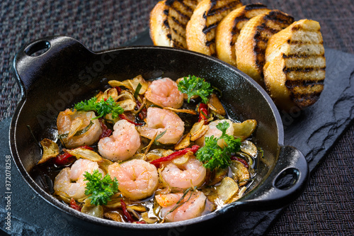gambas al ajillo, garlic prawns shrimp, spanish tapas in cast iron pan with toast