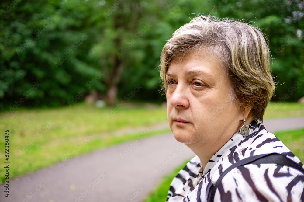 A Mature sad woman is resting in a city Park