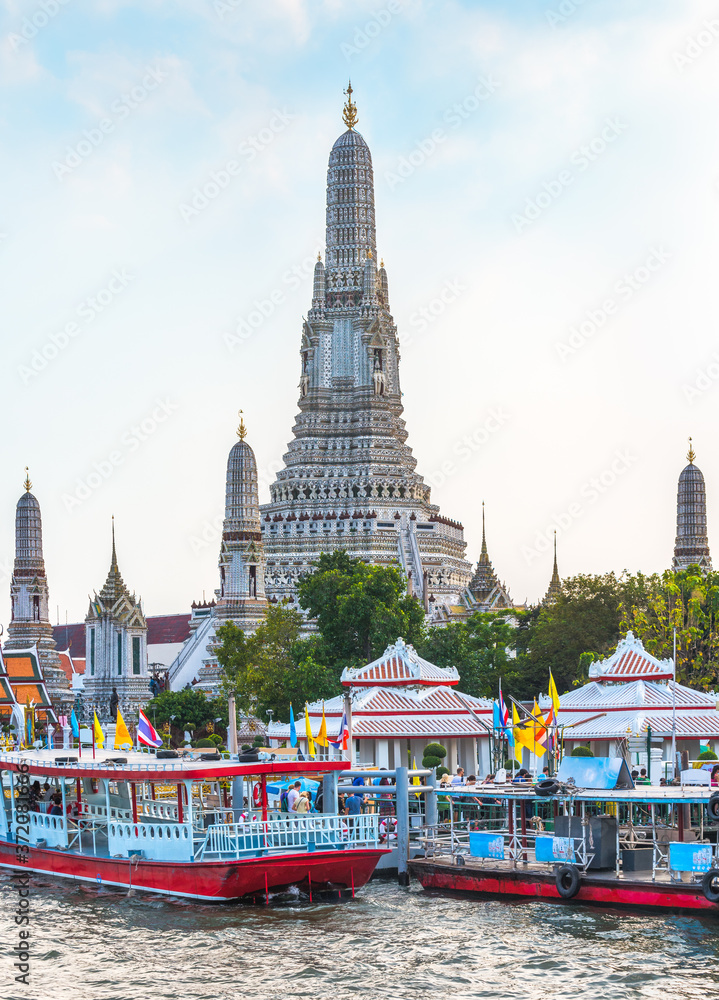 Boats on Chao Phraya River and Wat Arun, The Temple of Dawn, an Important Buddhist Temple and a Famous Tourist Destination in Bangkok Yai District of Bangkok, Thailand.