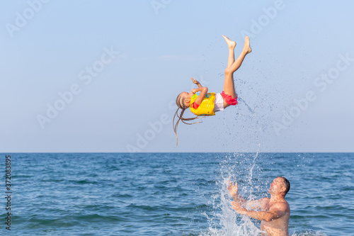 Schilderij op canvas A strong Caucasian man in sea tosses a 4-5 year girl