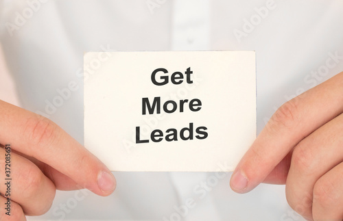 Man's hands take a card with words Get more leads, finance and business concept.