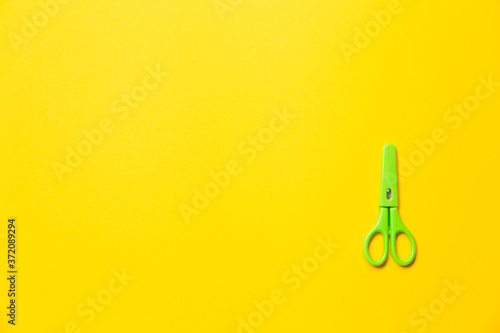 Small green scissors for children's creativity and applique making. Sharp dangerous tool in a case for safety and health. Banner on the theme of education with free space for text placement.