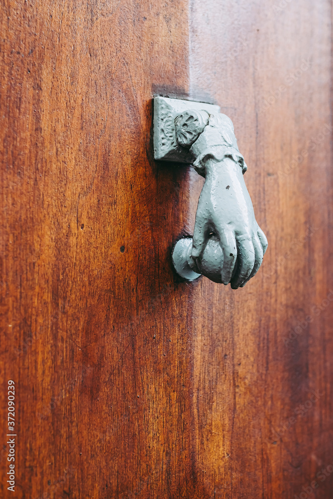 Heurtoir métallique en forme de main sur une porte en bois Stock Photo |  Adobe Stock