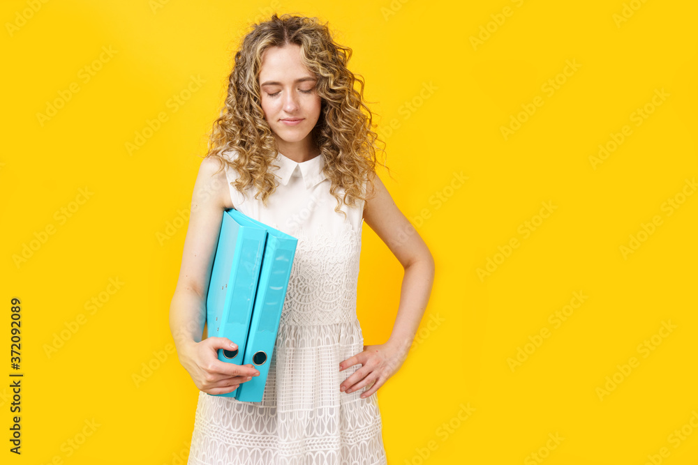 A young woman holds folders with documents in her hands.