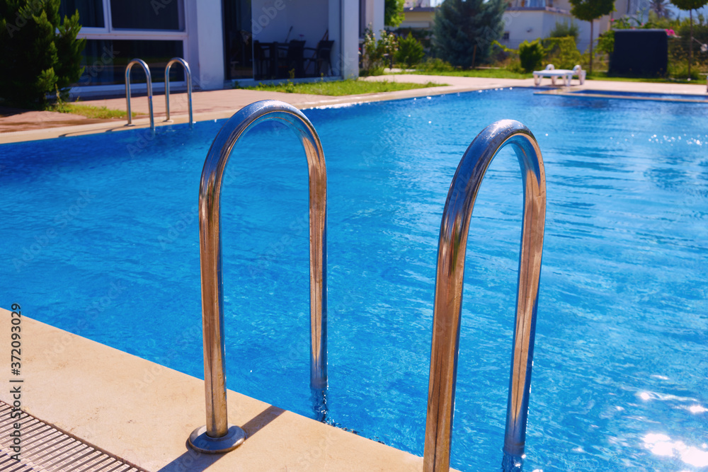 Hand rails of swimming pool. Metal entry ladder of swimming pool
