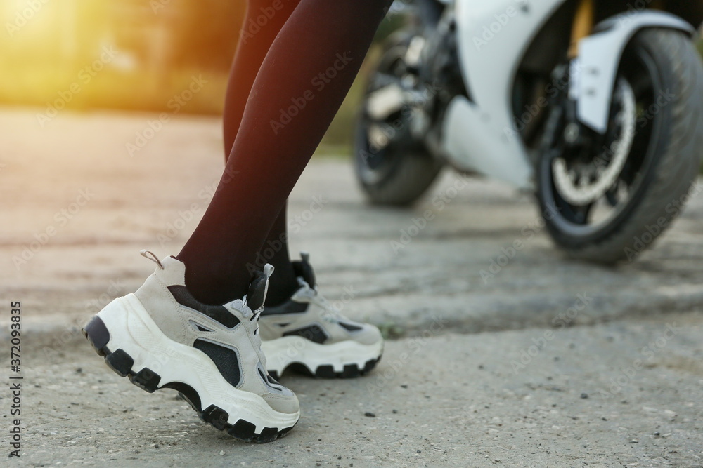 sneakers on female legs on motorcycle background close up