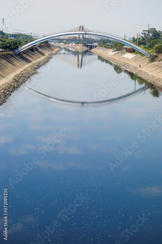 dark waters of Tiete river reflecting the sky and bridge. Sao Paulo  Brazil 