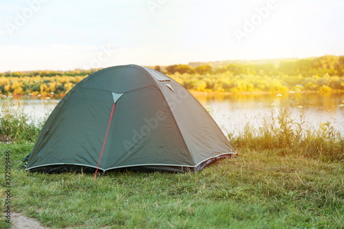 tourist tent on the high bank of the river at sunset