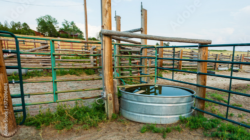 Stock tank and metal fence panels and wooden fencing in the animal corral on a working ranch near Denver