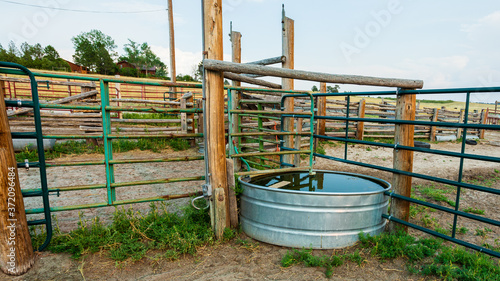 Stock tank and metal fence panels and wooden fencing in the animal corral on a working ranch near Denver photo